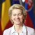 Portrait image of Ursula von der Leyen, President of the European Commission, standing in front of EU nation flags.