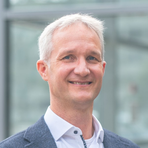 Headshot portrait of Sebastian Luber, Director Technology & Innovation at Infineon Technologies, in front of an office building.