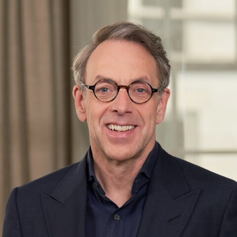 Headshot portrait of investor Klaus Hommels, founder of Lakestar and Chairman of the NATO Innovation Fund, seen indoors wearing a black shirt and glasses, smiling at the camera.