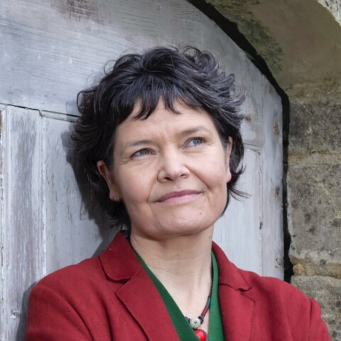 Environmental portrait of economist Kate Raworth, leaning on a wall, looking to the sky.