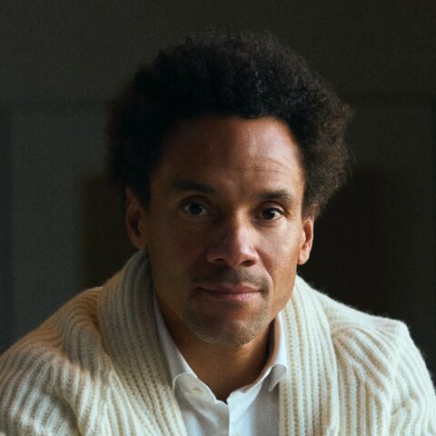 Artistic headshot portrait of BMW designer Oliver Heilmer, looking at the camera, his left side brightly lit, the right side mostly dark.