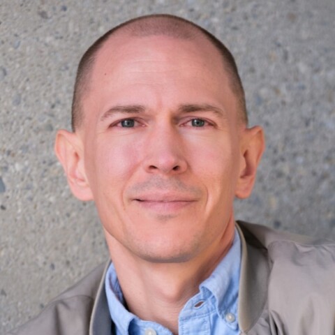 Portrait of German journalist and author Jannis Br&uuml;hl in front of a grey wall.