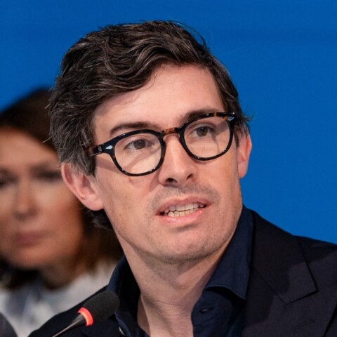 Investor and cryptocurrency manager Benjamin Habbel, Tether, speaking at an event, with other people visible in the background.