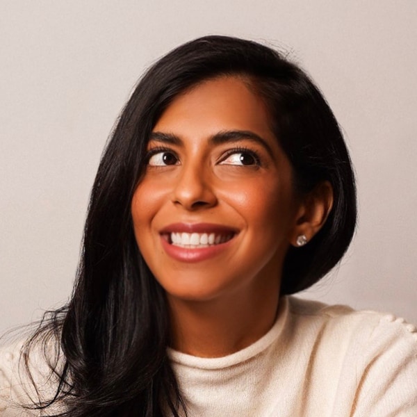 Portrait image of podcast host Nayeema Raza, looking up left, smiling.