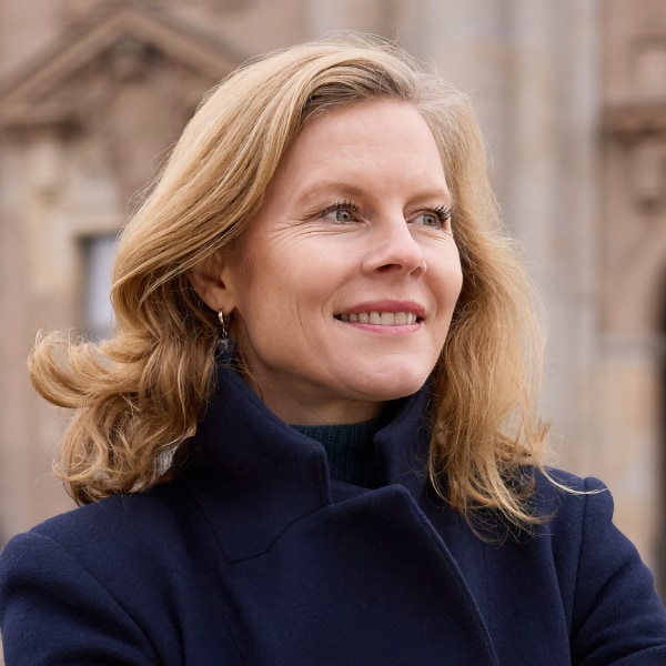 Outdoor portrait of impact investor Saskia Bruysten, standing in front of a historic building, looking to the right outside the frame.