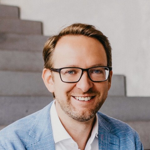 Environmental portrait of SAP executive Thomas Saueressig, sitting on a set of concrete stairs, smiling at the camera.