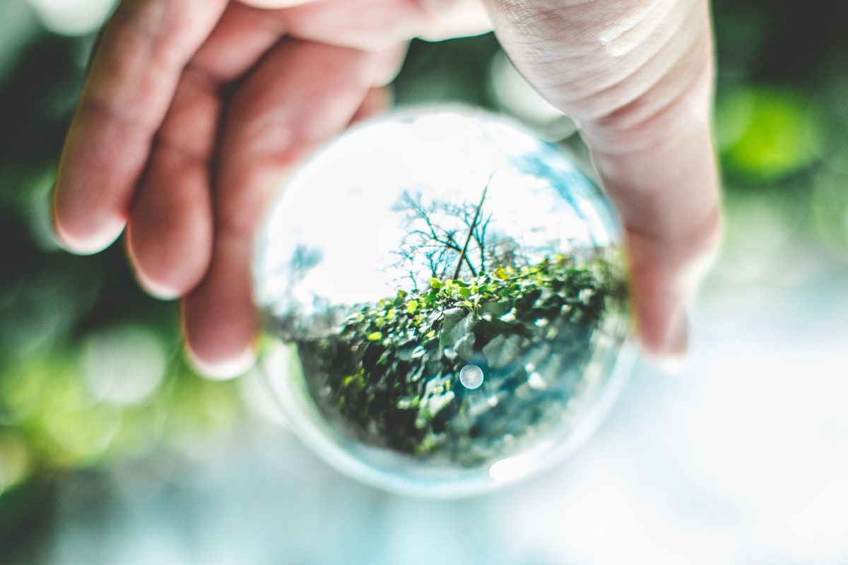 Hand holding a lens ball, upside down, symbolizing economic change towards sustainability and a circular economy