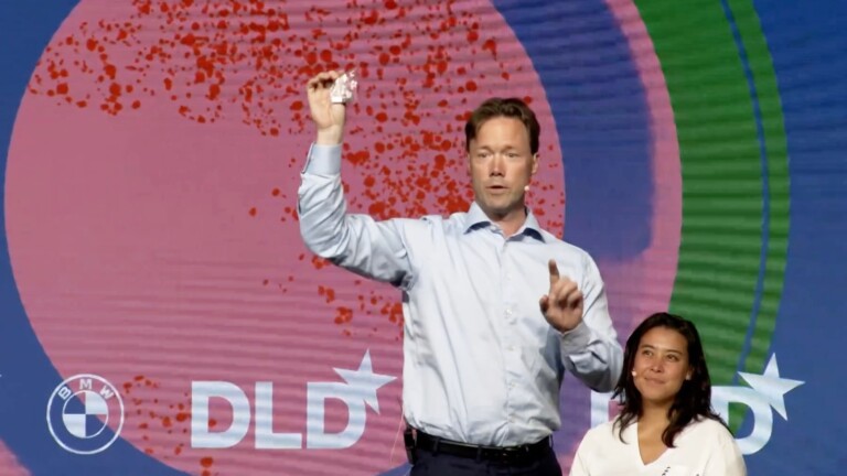 Benedikt Sobotka, CEO of the Eurasian Resources Group, shows rare metals that go into batteries of electric vehicles to attendees of the DLD Circular 2023 conference. In the background, tozero co-founder Sarah Fleischer watches, smiling.