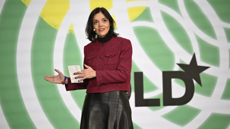 Ana Paula Assis, General Manager IBM Europe, standing in front of a colorful video screen as she’s giving a talk about AI in business at the DLD Munich 2024 conference.