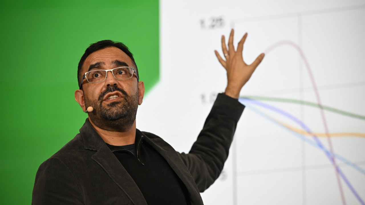 Analyst Azeem Azhar speaks about digital transformation at the DLD Munich 2024 conference, pointing at a chart behind him on a video wall.