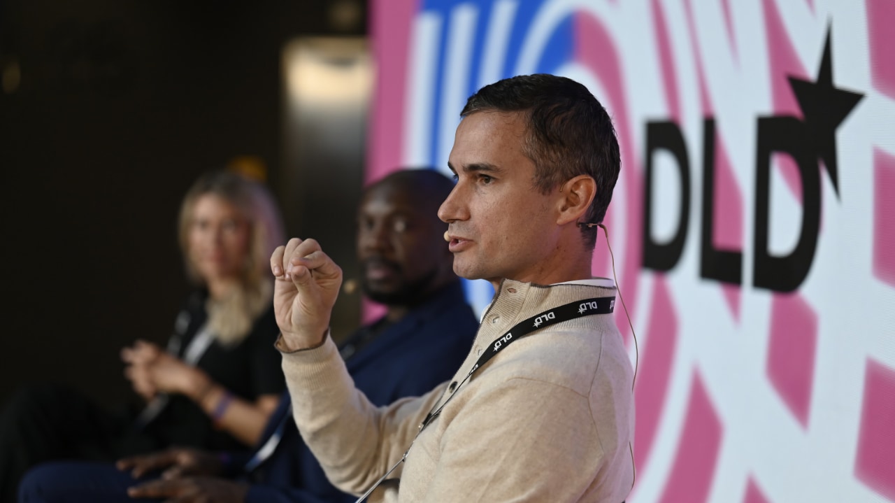 Close-up of investor Dirk van Quaquebeke (BEENEXT) speaking at the DLD Munich conference 2024, with other panelists visible in the background.
