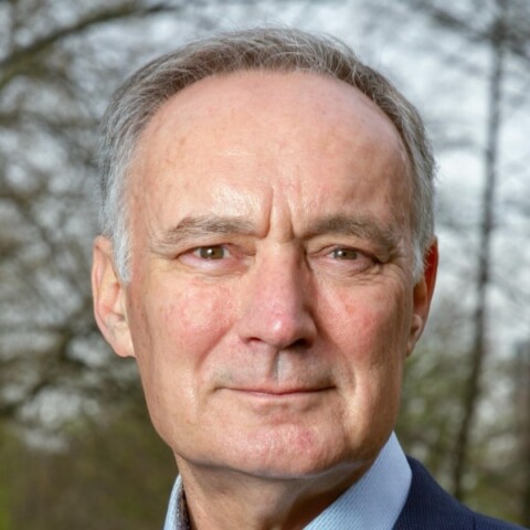 Close-up portrait of retired General Tom Middendorp, Chairman of the International Military Council on Climate and Security, wearing a suit, looking straight at the camera.