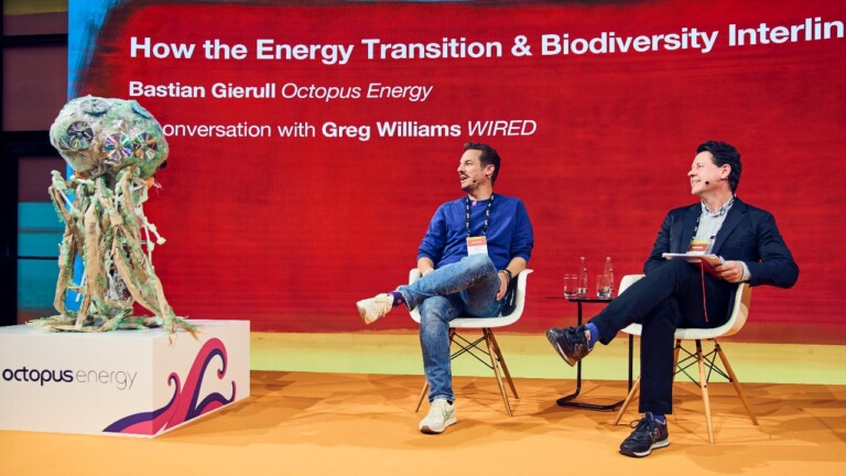 Bastian Gierull (Octopus Energy) in conversation with Greg Williams (WIRED) at the DLD Nature conference. Both look at a colorful skulpture of an octopus.