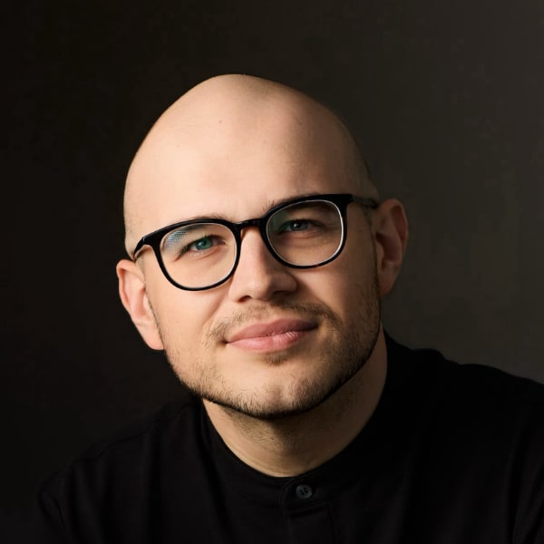 Dramatically lit studio portrait image of Kor Kajanaku, co-founder and CEO of OpenStudio. The left side of his face is brightly lit, the right side lies mostly in the dark.