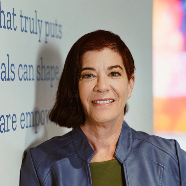 Portrait image of Mitchell Baker, co-founder and Executive Chair of the Board of Mozilla, in front of a billboard showing the foundation’s core mission.