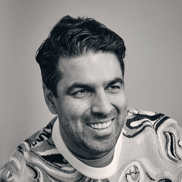 Black-and-white portrait of Sachin Dev Duggal, Founder of software company Builder.ai, smiling, looking to the right.