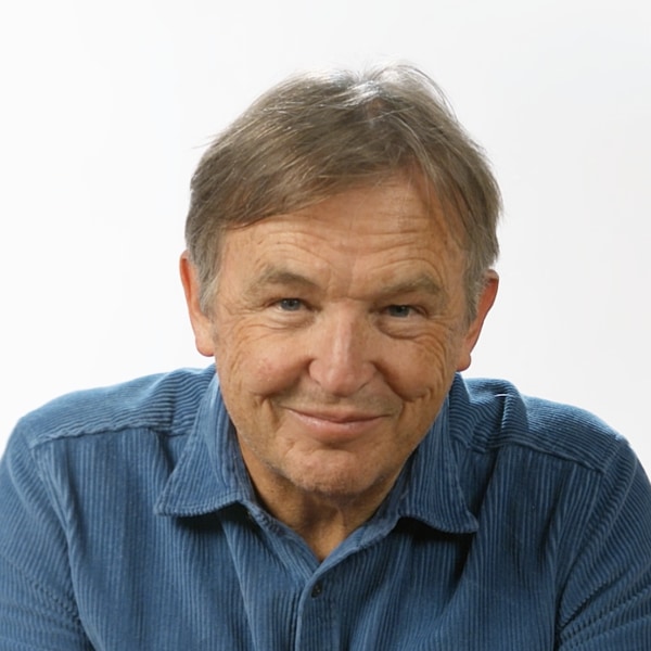 Portrait image of TED curator Chris Anderson, wearing a blue shirt in front of a white background, smiling at the camera.