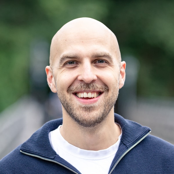 Outdoor portrait of AI entrepreneur David Hahn, CEO and Co-Founder of Remberg, smiling at the camera, nature visible in the background.