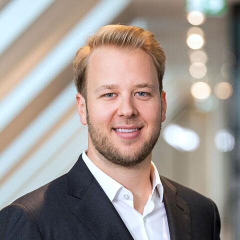 Portrait image of investor Maximilian Kuss, Co-Founder of EMH Partners, standing in a neon-lit room, smiling at the camera.