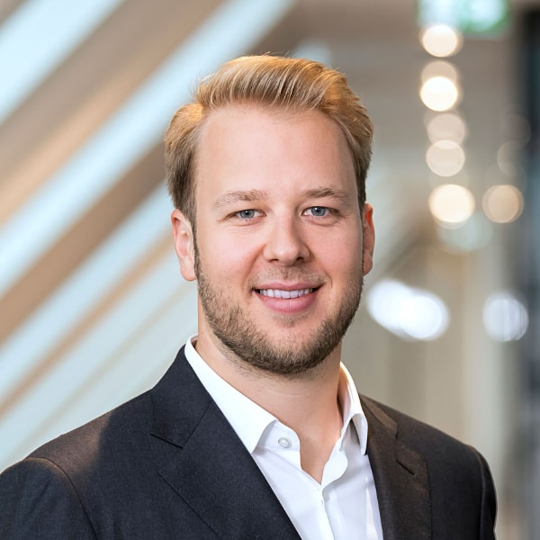 Portrait image of investor Maximilian Kuss, Co-Founder of EMH Partners, standing in a neon-lit room, smiling at the camera.