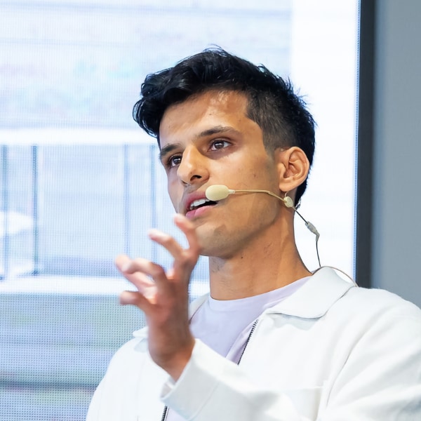 Headshot of Shravan Nageswaran, CEO of AI company Atman Labs, standing in front of a screen, talking while wearing a headset and gesticulating with his left hand.