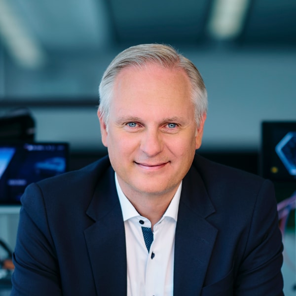 Portrait image of BMW manager Stephan Durach in a neon-lit room, surrounded by displays and engineering equipment.