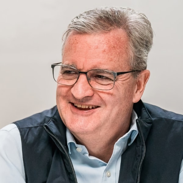 Portrait image of Zeki Data CEO Tom Hurd, smiling, looking left, wearing a black vest and glasses.