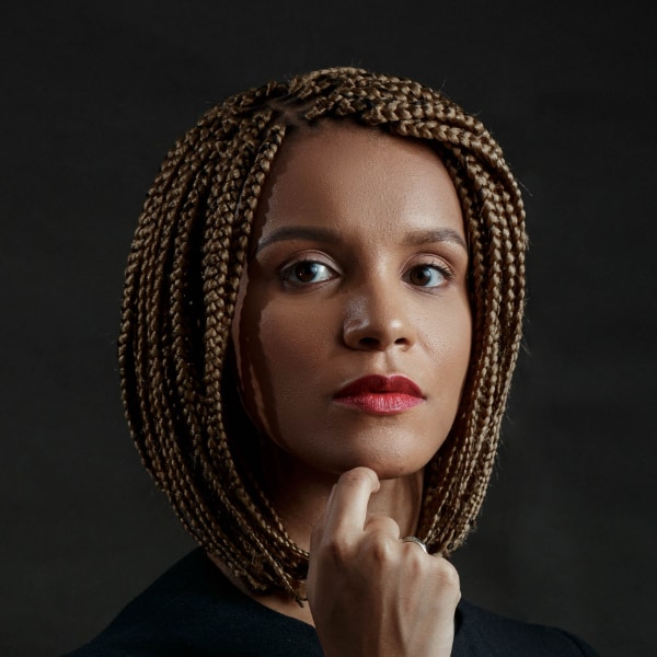 Studio portrait Yasmin Kumi, Founder and CEO of Africa Foresight Group, in front of a dark background, looking at the camera.