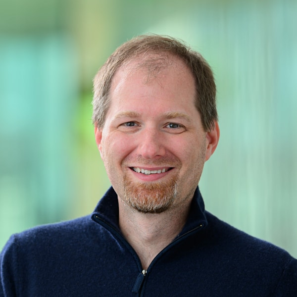 Headshot portrait photo of Bob Mumgaard, CEO and Co-founder of cleantech company Commonwealth Fusion Systems, seen in front of a blue-green, blurry background.