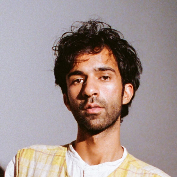 Studio portrait of historian, DJ and broadcaster Haseeb Iqbal in front of a grey background.