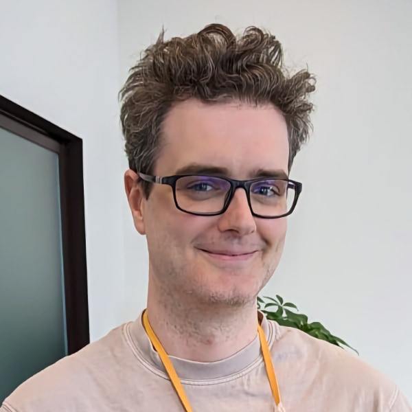 Casual indoor portrait of AI researcher Llion Jones in a room with plants in the background.