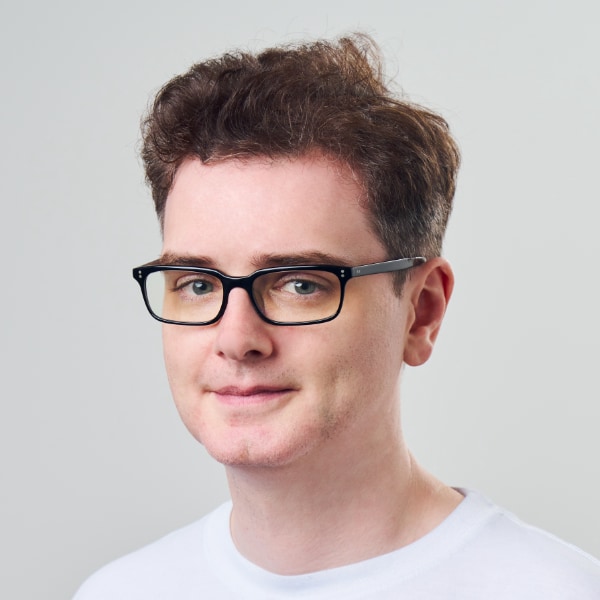 Studio headshot portrait of AI researcher Llion Jones, Sakana AI, in front of a neutral grey background.