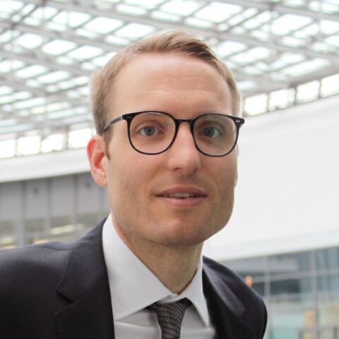 Portrait of BMW manager Michael Rath, seen in an industrial building, looking at the camera.