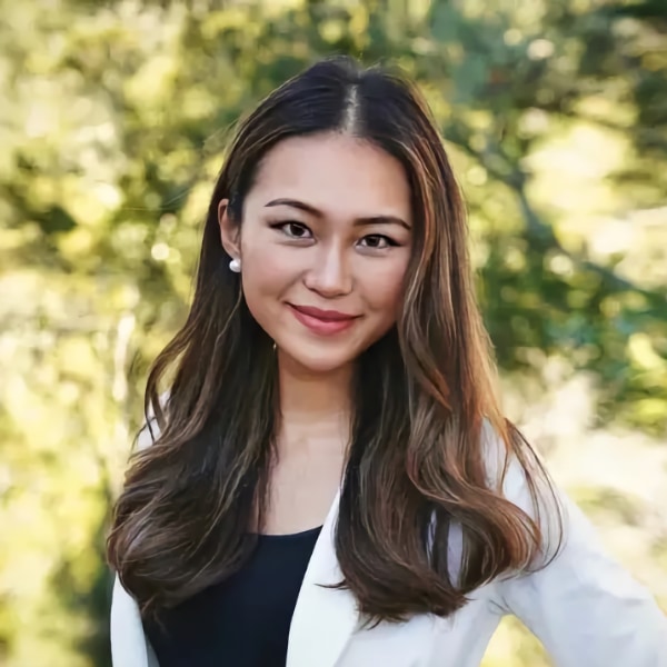 Environmental portrait of Moonshot AI founder Nancy Xu, smiling at the camera, seen outside in nature on a sunny day.