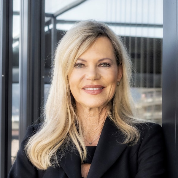 Portrait of German TV presenter and longevity consultant Nina Ruge, standing outdoors in front of a building.