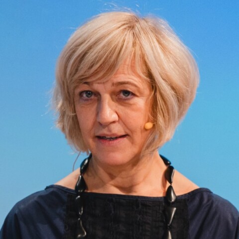 Portrait photo of Renate Nikolay, Deputy Director of DG CONNECT, speaking at a conference in front of a blue background.
