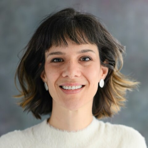 Headshot portrait of astrophysicist Cecilia Garraffo in front of a grey background, smiling at the camera