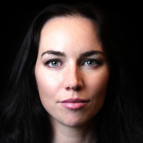 Close-up studio portrait of TV presenter and poker player Liv Boeree, dramatically lit in front of a black background.