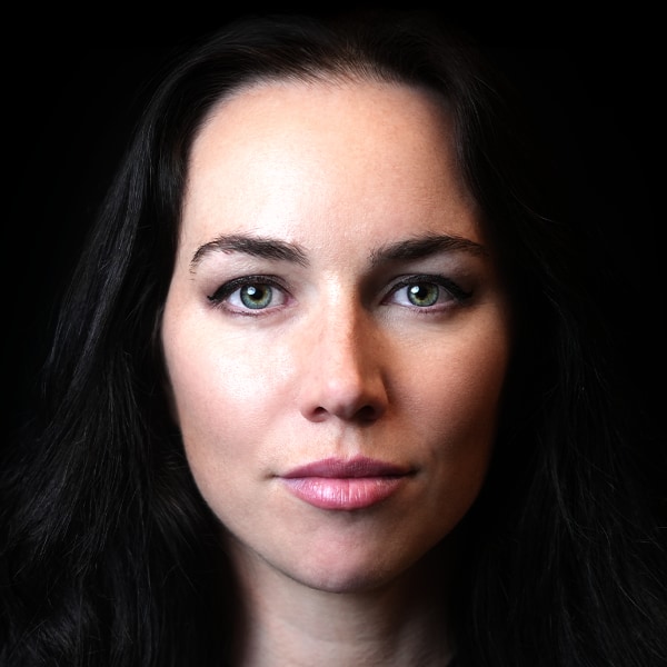Close-up studio portrait of TV presenter and poker player Liv Boeree, dramatically lit in front of a black background.