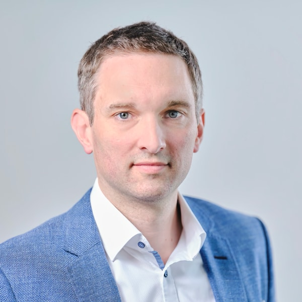 Studio headshot portrait of Dr. Michael Förtsch, founder and CEO of Q.ANT, in front of a neutral grey background.