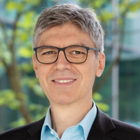 Headshot portrait of robotics expert Alin Albu-Schäffer, DLR, Technical University Munich, in front of a colorful outdoor background.