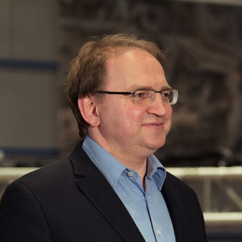 Headshot portrait of MP3 co-inventor Bernhard Grill, Director at Fraunhofer IIS, standing in a lab.