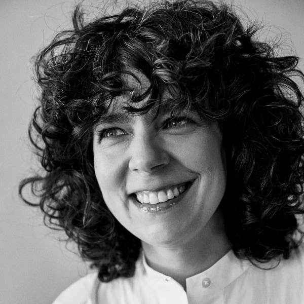 Black-and-white headshot portrait of Carol Blázquez, Chief Purpose Officer at fashion company Ecoalf, looking left, smiling.