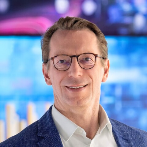 Headshot portrait of Brainlab CEO Rainer Birkenbach in front of a colorful background.