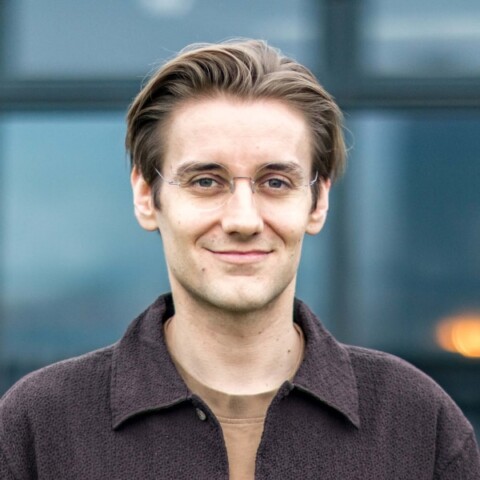Headshot portrait of AI expert Dr. Simon Kohl, founder of Latent Labs, in front of a dark grey background.