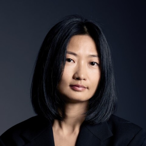 Headshot portrait of art curator Xue Tan, brightly lit in front of a dark background.