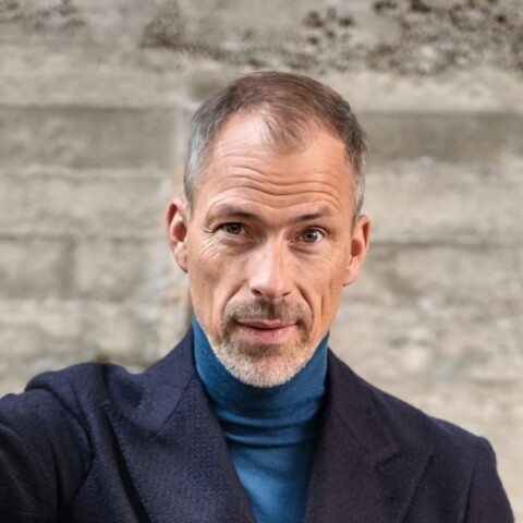 Outdoor headshot portrait of Anders Warming, BMW Group, in front of a grey wall.
