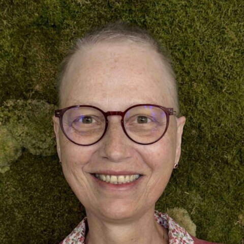 Headshot portrait of Andrea Martin, IBM, in front of a green, grassy background.