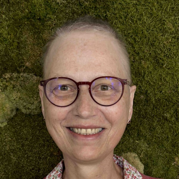 Headshot portrait of Andrea Martin, IBM, in front of a green, grassy background.