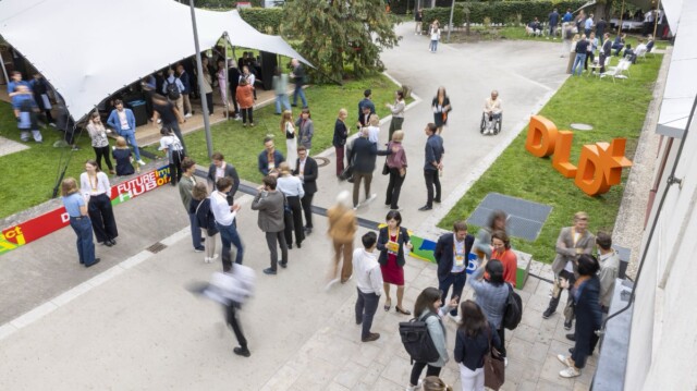DLD Future Hub audience seen from a window of Amerikahaus in Munich. People are mixing and mingling outdoors.